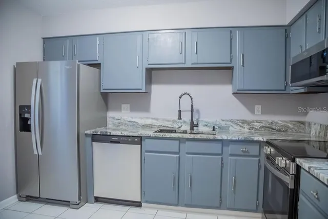 a kitchen with stainless steel appliances granite countertop a refrigerator and a sink