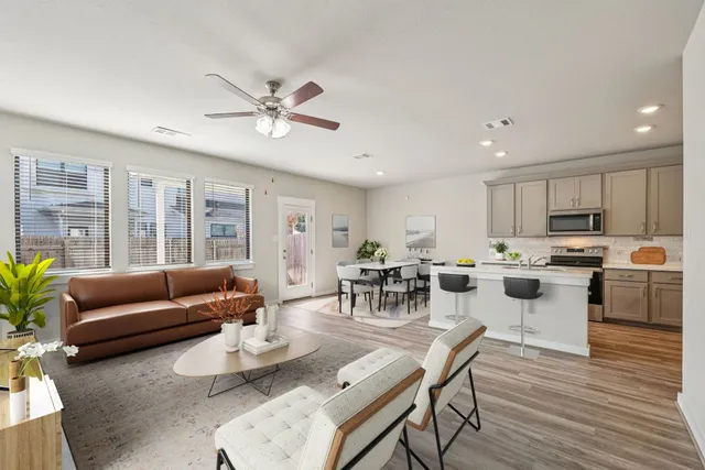 a living room with furniture kitchen and a wooden floor