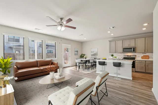a living room with furniture kitchen and a wooden floor