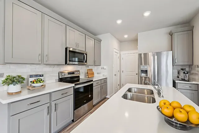 a kitchen with stainless steel appliances granite countertop a sink a stove a refrigerator cabinets and a window