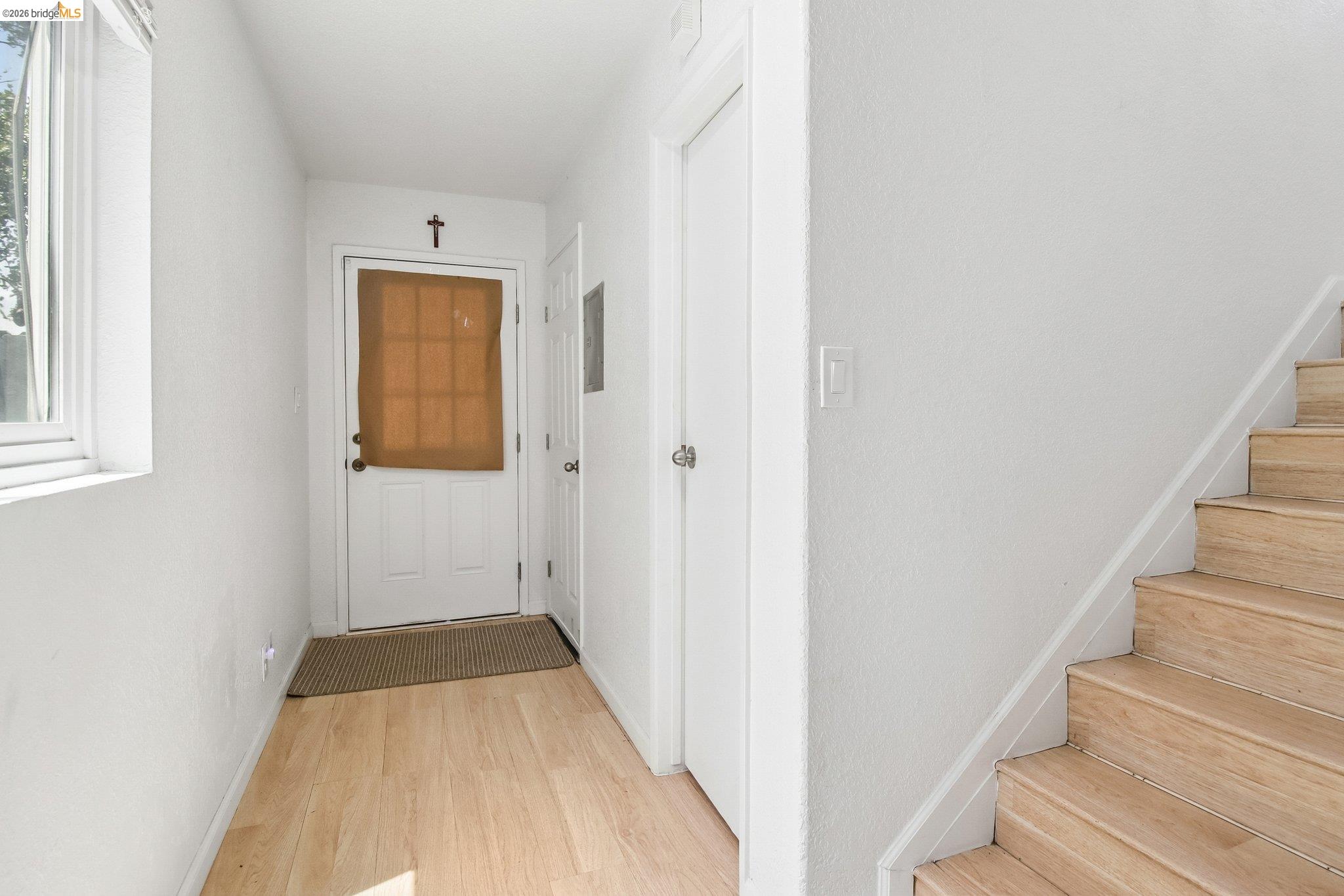 874 Pine Street Oakland, CA 94607 - Photo 3 of 39 Entryway featuring wood-finish flooring, white painted walls, and a staircase with wood-finish treads