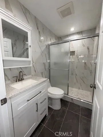 a bathroom with a granite countertop sink toilet and shower