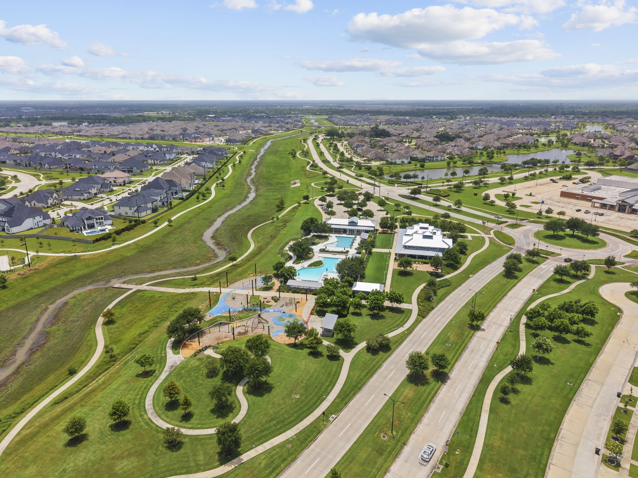 2011 Oak Leaf Court Manvel, TX 77578 - Photo 26 of 28 Well-planned suburban neighborhood with winding roads, lush green spaces, and a central recreational area featuring a pool and playground. The community is surrounded by neatly arranged houses and offers ample open areas for outdoor activities.