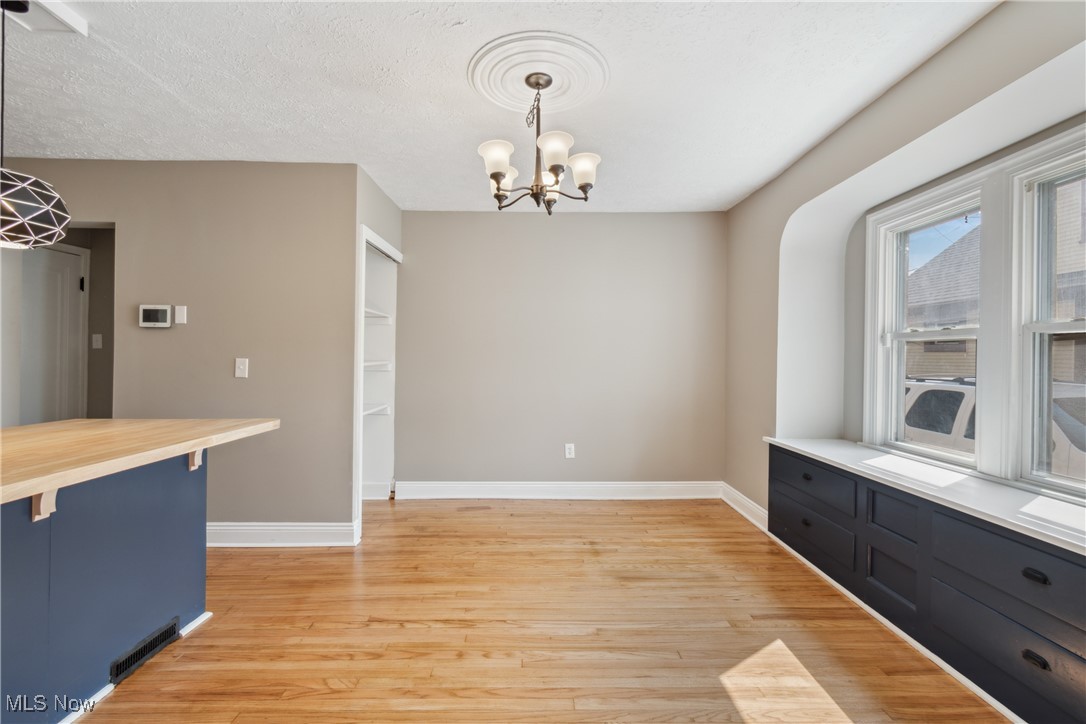 451 West Waterloo Road Akron, OH 44314 - Photo 12 of 27 Unfurnished dining area featuring a textured ceiling, a chandelier, and light hardwood / wood-style floors