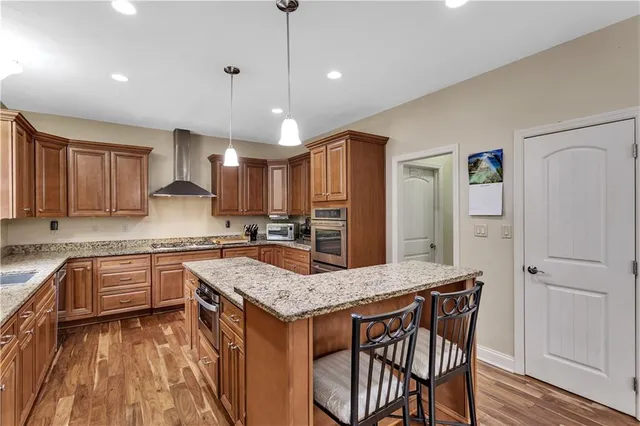 a kitchen with granite countertop a stove a sink dishwasher a refrigerator with wooden cabinets and floor