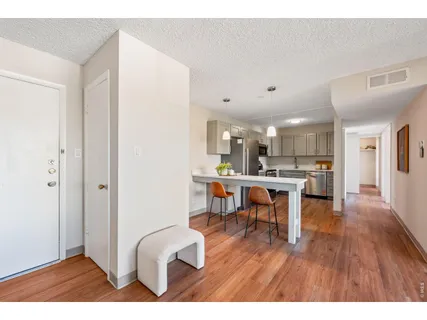 a living room with kitchen view and a wooden floor