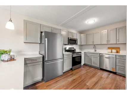 a open kitchen with cabinets wooden floor and stainless steel appliances