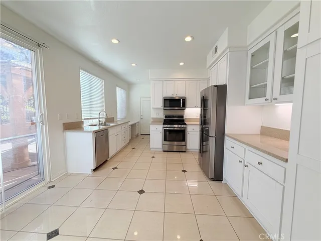 a room with stainless steel appliances kitchen island granite countertop a refrigerator and cabinets