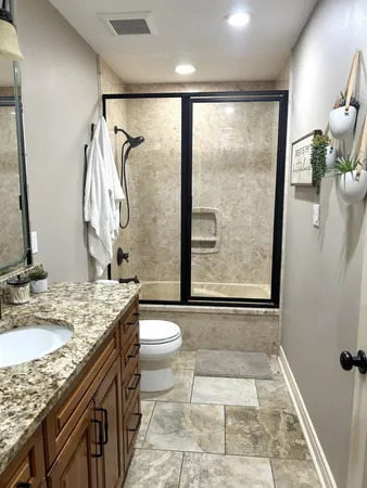 a bathroom with a granite countertop sink toilet and shower