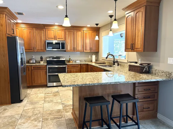 a kitchen with stainless steel appliances granite countertop a table chairs sink refrigerator and microwave