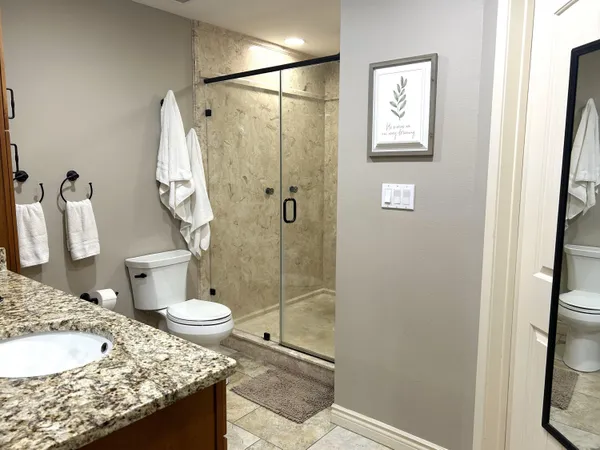 a bathroom with a granite countertop sink toilet and shower