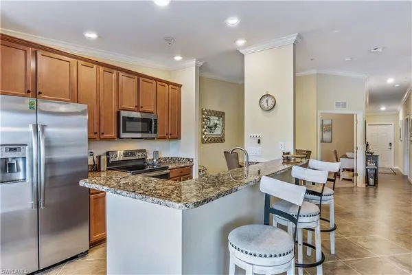 a kitchen with a refrigerator a stove a sink and chairs