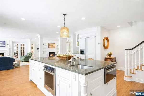 a kitchen with granite countertop a sink dishwasher a stove and a dining table with wooden floor