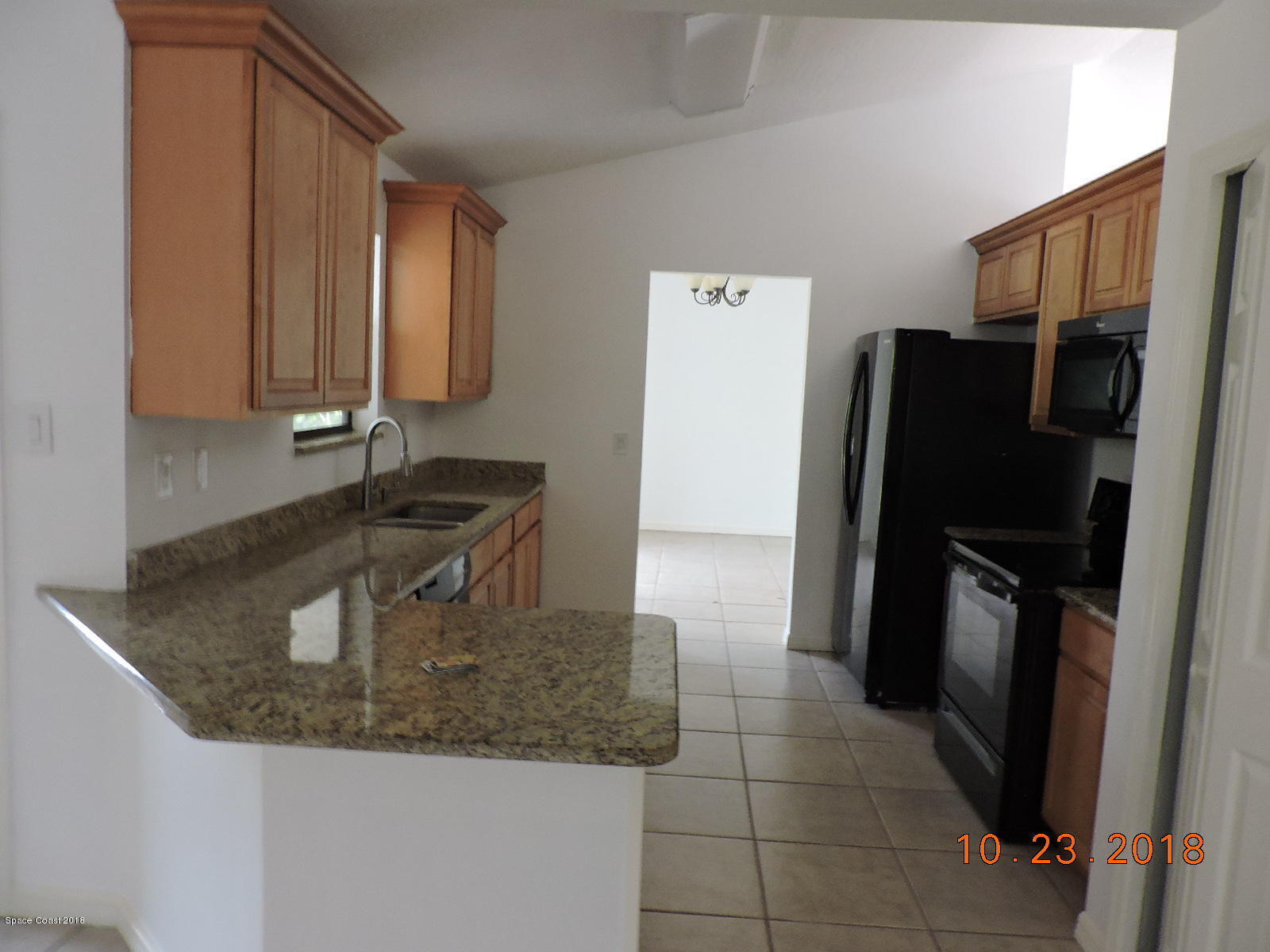 2195 Ladner Road Northeast Palm Bay, FL 32907 - Photo 6 of 14 a kitchen with granite countertop a refrigerator and a sink