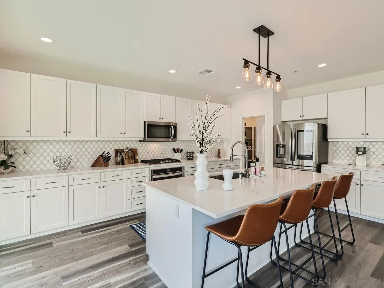 1263 Spivey Road Chula Vista, CA 91913 - Photo 3 of 26 a kitchen with stainless steel appliances kitchen island granite countertop a stove a sink a refrigerator and white cabinets