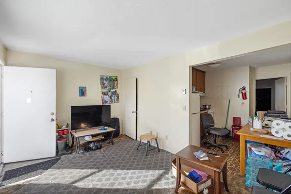 a living room with furniture a flat screen tv and a refrigerator