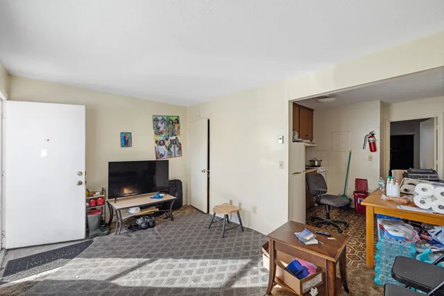 a living room with furniture a flat screen tv and a refrigerator