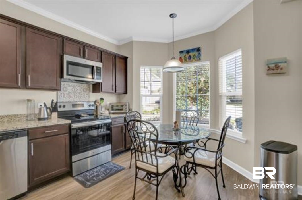 430 West Fort Morgan Road Gulf Shores, AL 36542 - Photo 24 of 27 Kitchen featuring dark wood cabinetry, stainless steel appliances, speckled countertops, and a tiled backsplash