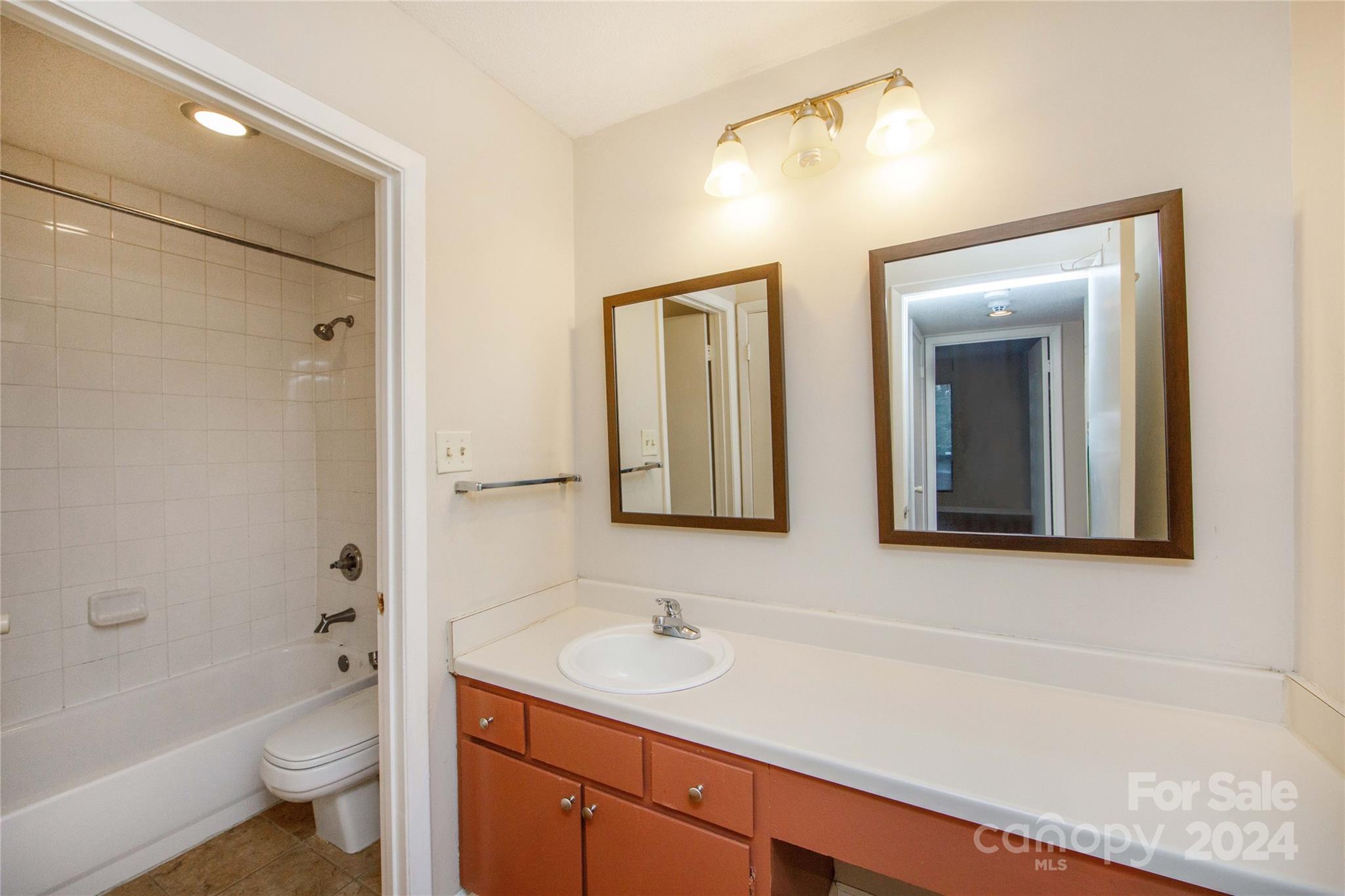 5020 Sardis Road, Unit E Charlotte, NC 28270 - Photo 21 of 27 a bathroom with a sink a toilet and a large mirror