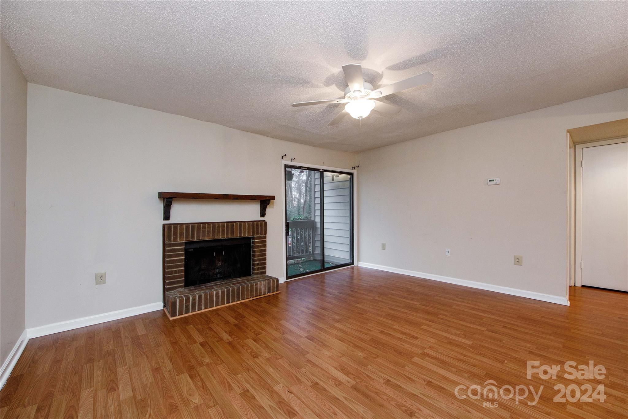 5020 Sardis Road, Unit E Charlotte, NC 28270 - Photo 4 of 27 a view of an empty room with wooden floor fireplace and a window