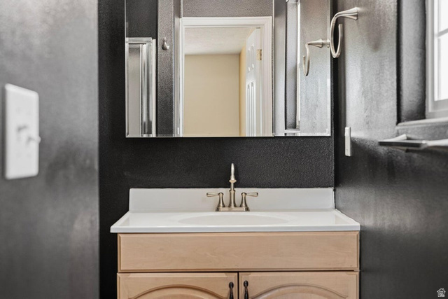 132 Rex Layne Drive Central, UT 84722 - Photo 23 of 39 Bathroom vanity with a light wood-finish cabinet, white countertop, and brushed nickel faucet