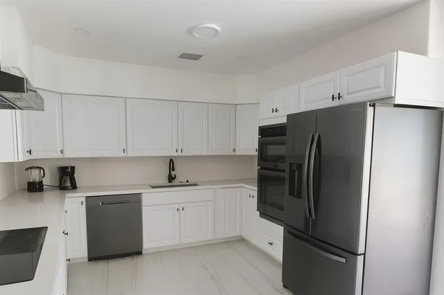 a kitchen with a refrigerator sink and cabinets