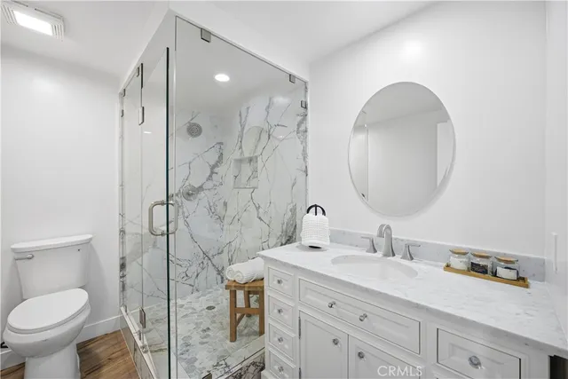 a bathroom with a granite countertop sink mirror vanity and toilet