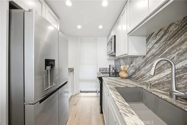 a kitchen with stainless steel appliances granite countertop a sink and a refrigerator