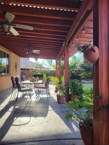 a view of a patio with table and chairs potted plants and floor to ceiling window