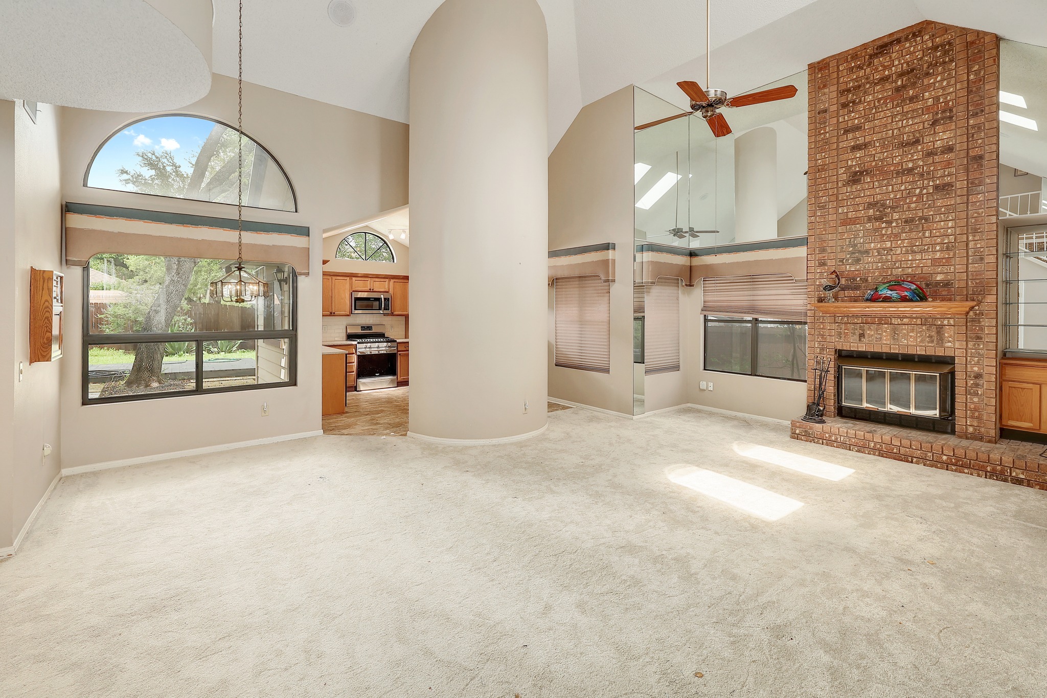 2202 Warfield Way Austin, TX 78728 - Photo 3 of 32 A spacious living area featuring high ceilings, a cozy fireplace, and an adjoining kitchen.