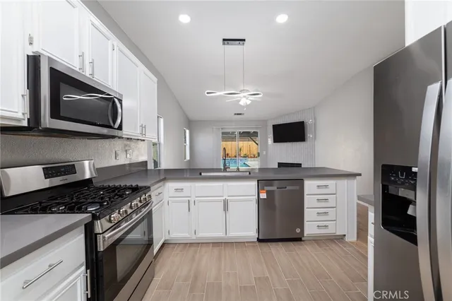 a kitchen with stainless steel appliances white cabinets a sink and a stove