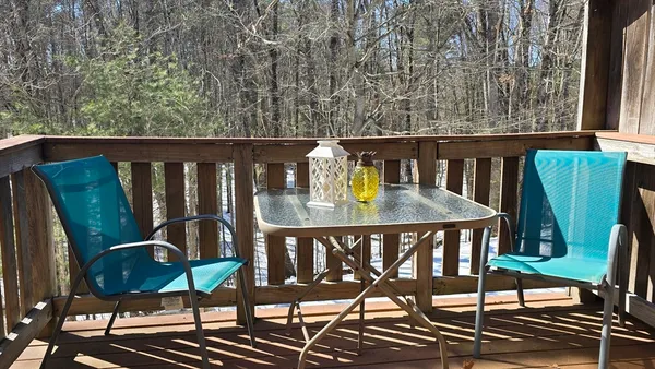 a balcony with wooden floor table and chairs