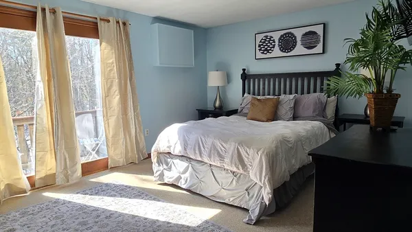 a bedroom with a bed lamp and a large window