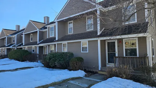 a view of a brick house with many windows next to a yard