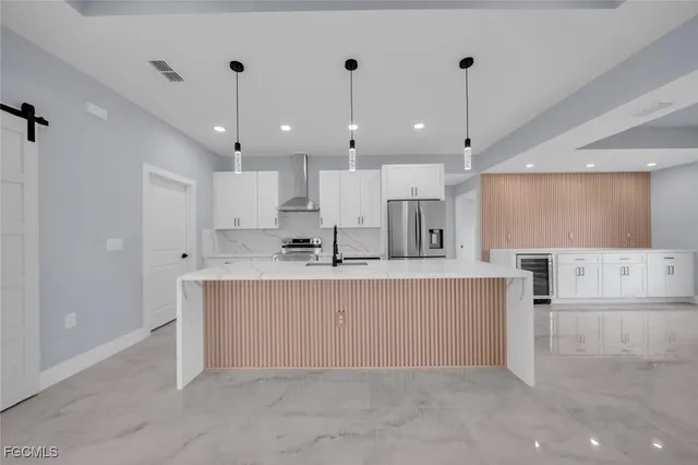 a view of kitchen with kitchen island a sink stainless steel appliances and a counter top