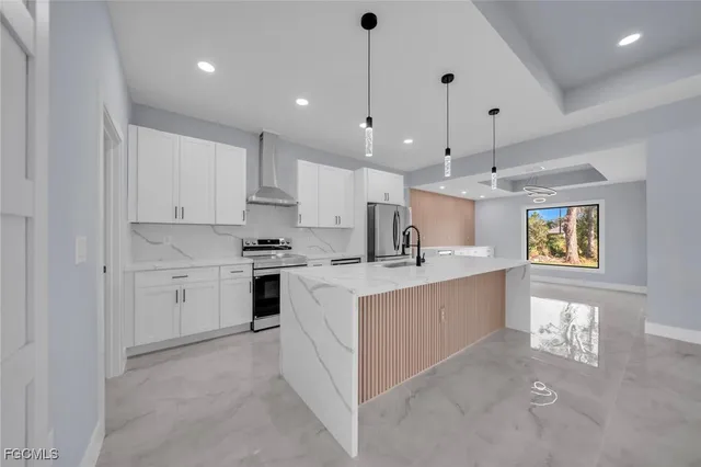 a large white kitchen with kitchen island a sink stainless steel appliances and cabinets