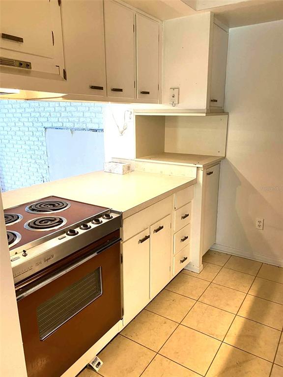 1935 South Conway Road, Unit D1 Orlando, FL 32812 - Photo 6 of 21 a kitchen with granite countertop a stove a sink dishwasher and white cabinets with wooden floor