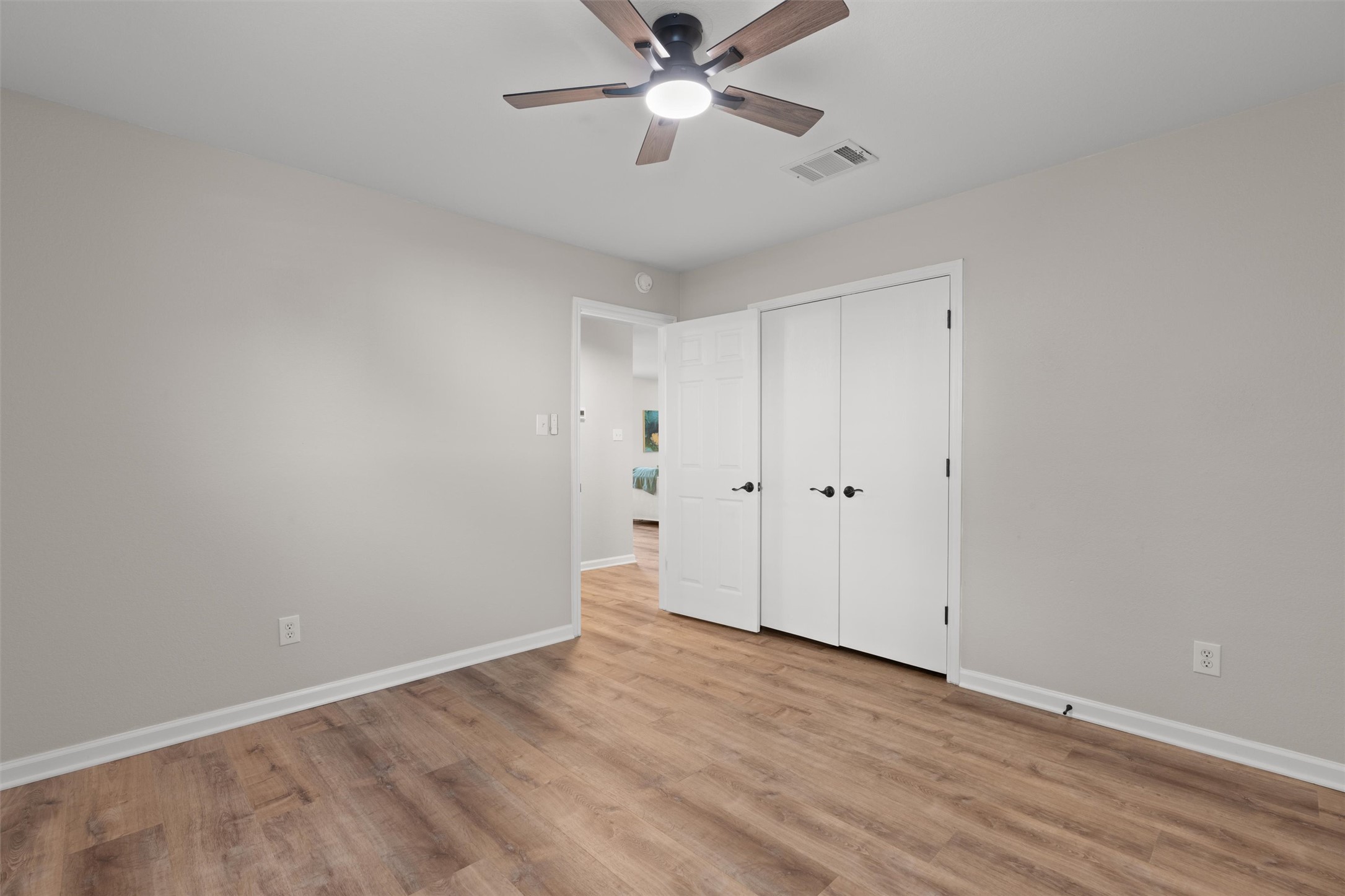 724 Lavaca Loop Elgin, TX 78621 - Photo 23 of 40 Smooth wood floors and neutral walls anchor this clean and inviting bedroom space.
