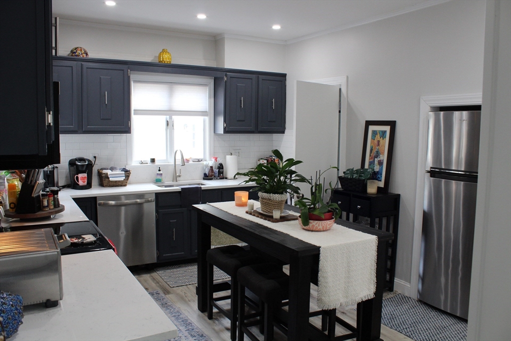 295 Haven Reading Ma, Unit 1 Reading, MA 01867 - Photo 2 of 16 a kitchen with a table chairs refrigerator and microwave