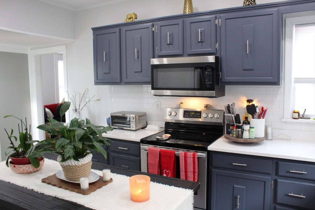 295 Haven Reading Ma, Unit 1 Reading, MA 01867 - Photo 4 of 16 a kitchen with a microwave a stove and cabinets