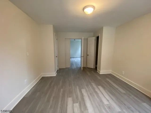 an empty room with wooden floor and bathroom