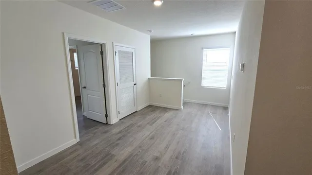 an empty room with wooden floor and windows