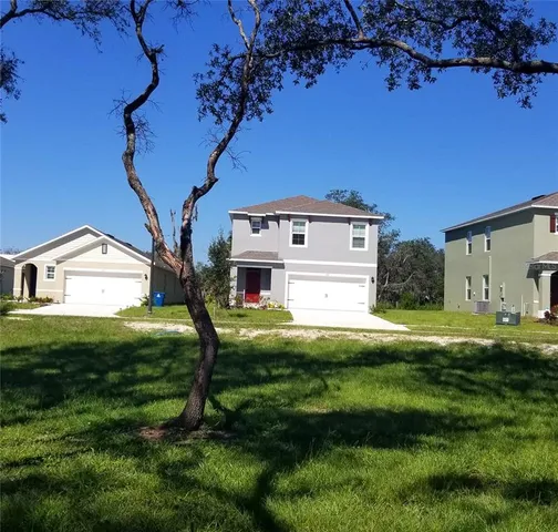 a view of a house with a big yard potted plants and large tree