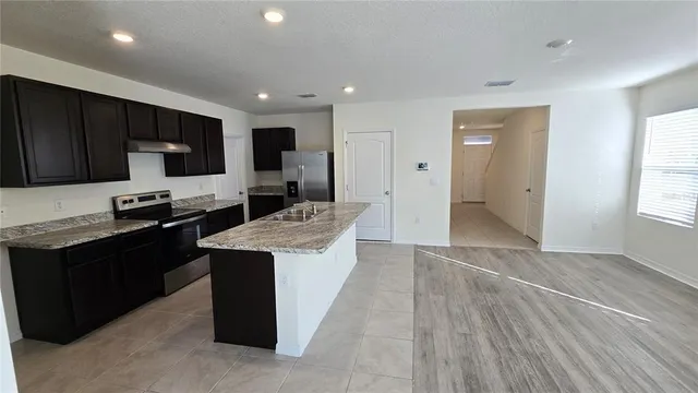 a kitchen with stainless steel appliances kitchen island granite countertop a stove a sink and a refrigerator