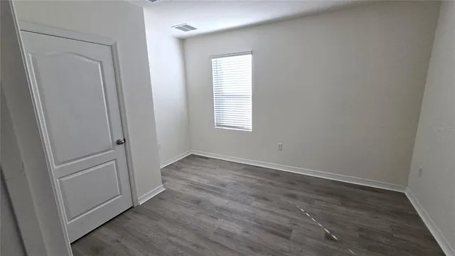 an empty room with wooden floor and window