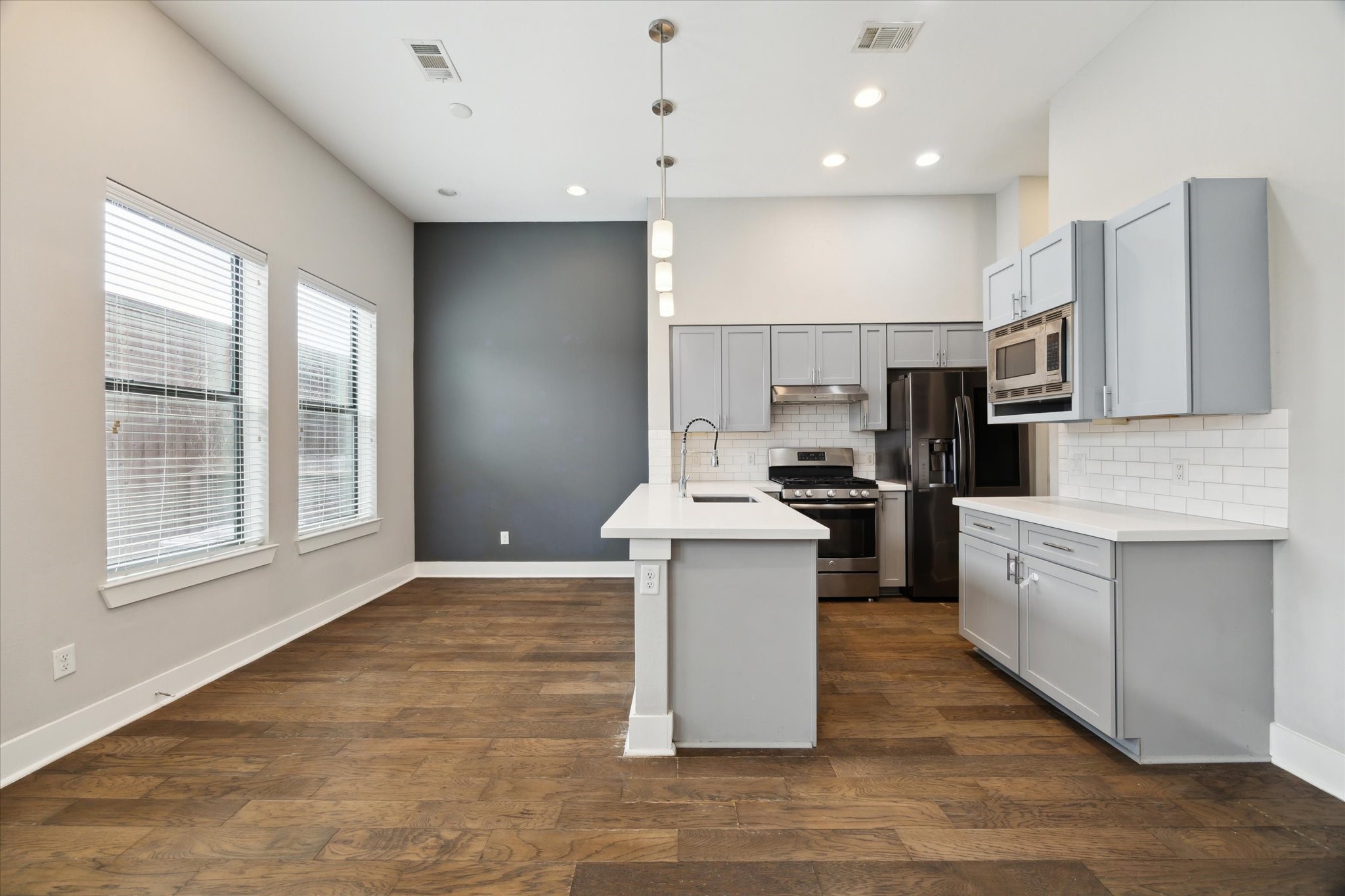 614 Thornton Road, Unit G Houston, TX 77018 - Photo 7 of 18 a kitchen with kitchen island granite countertop a stove top oven a sink dishwasher a refrigerator and white cabinets with wooden floor