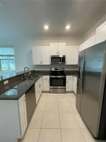 a large kitchen with granite countertop a stove a sink and a refrigerator