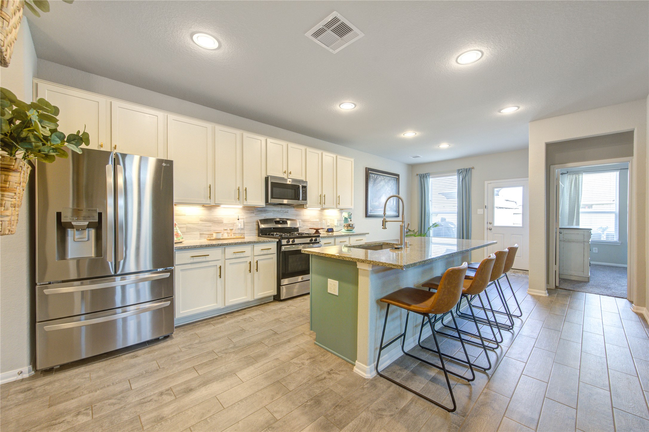 a kitchen with stainless steel appliances granite countertop a refrigerator a sink dishwasher a stove and white cabinets with wooden floor