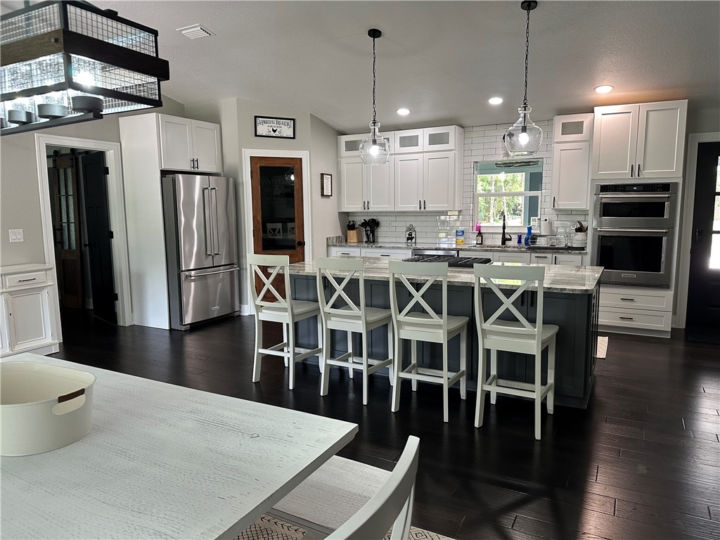 4135 Grant Road Grant Valkaria, FL 32949 - Photo 6 of 26 a kitchen with stainless steel appliances a dining table chairs stove refrigerator and cabinets