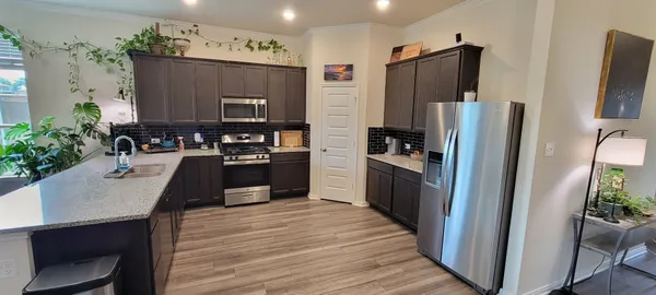 a kitchen with granite countertop a refrigerator stove and sink